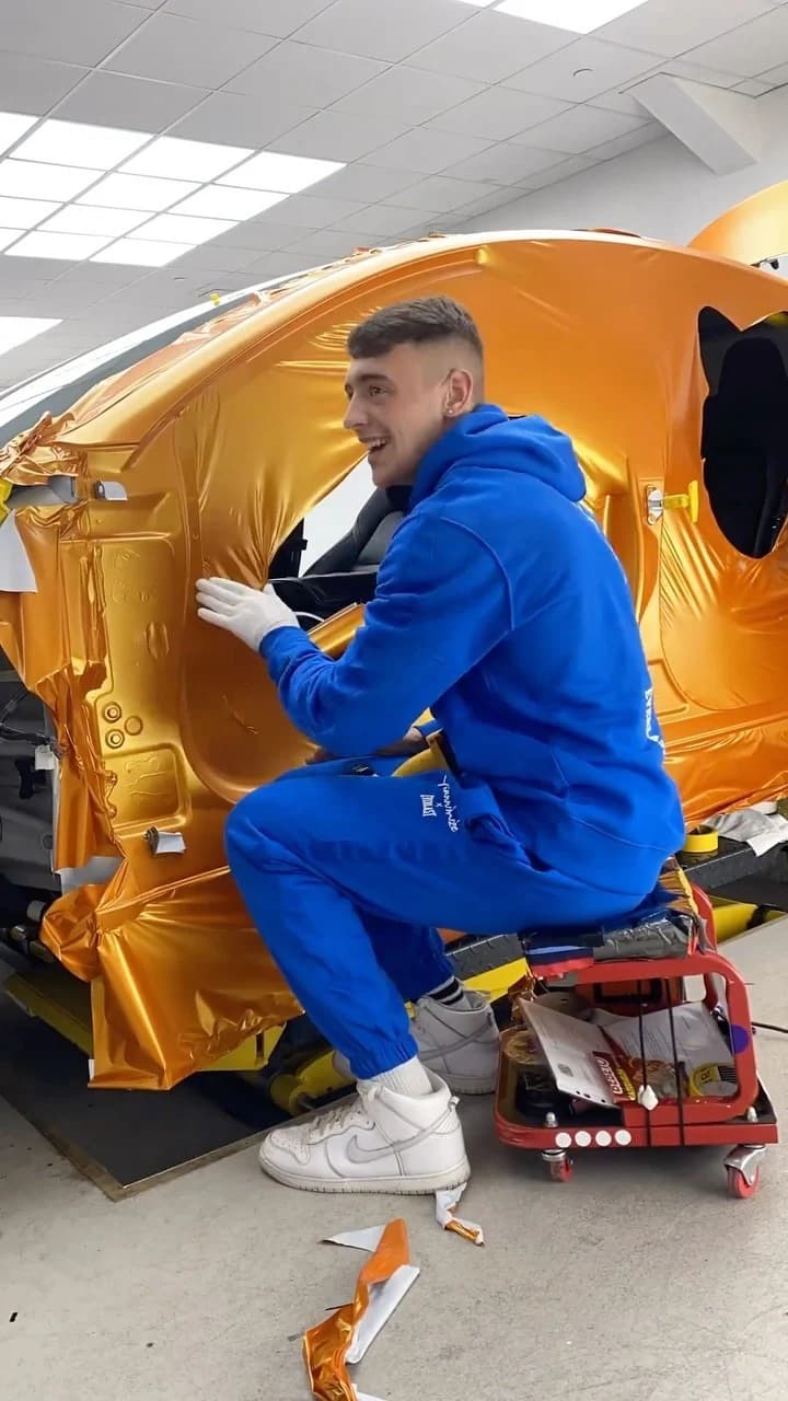 Kean crouched at a door shell, laying gloss orange vinyl by hand