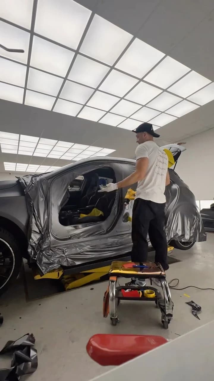 A team wrapping a car in a busy studio