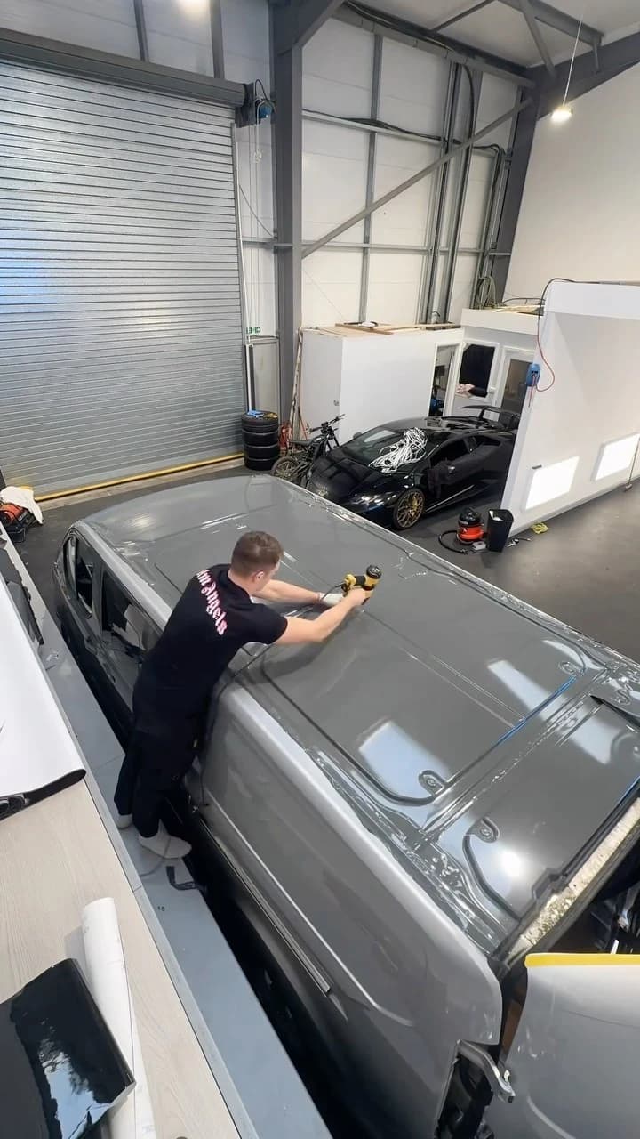 Kean applying vinyl to a van roof in the Cardiff studio